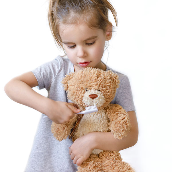 Girl brushing her teddy bear's teeth